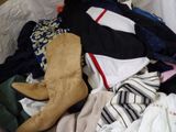 a pile of clothes and boots sitting on a bed