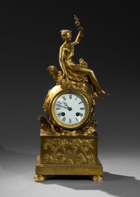 une horloge en or surmontée d'une dame assise
