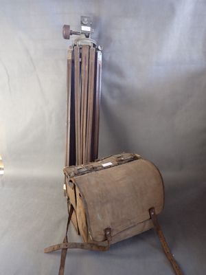 un sac en papier brun posé sur une chaise en bois, à côté d'un trépied