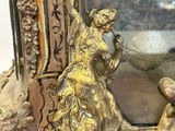 brass figurines of a woman and a man in front of a mirror