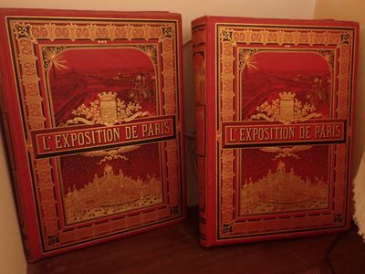 une paire de livres anciens peints en rouge et or, posés sur une étagère en bois