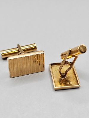 deux paires de boutons de manchette en or posés sur un fond blanc