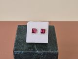 a pair of pink cubicge earrings sitting on top of a marble block