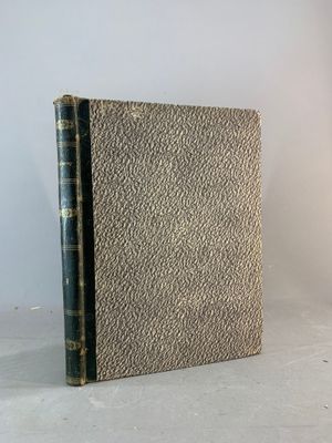 un vieux livre posé sur une table, à côté d'une lampe