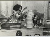 photographie en noir et blanc d'une femme en train de disposer des assiettes sur une table