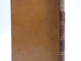 an old book sitting on top of a white table next to a white wall