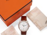 an orange box with a white watch and a brown leather strap
