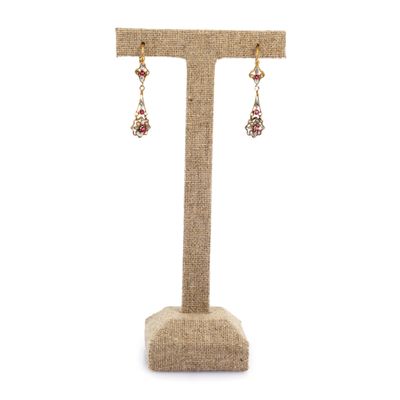 une paire de boucles d'oreilles rouges et dorées posées sur un présentoir
