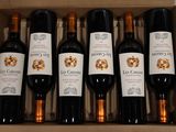 six bottles of wine in a cardboard box on a table