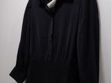 a black dress hanging on a white wall next to a hanger