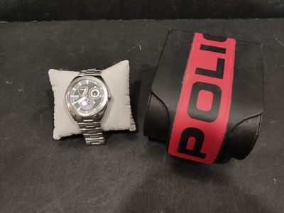 a watch sitting next to a pillow on a black surface