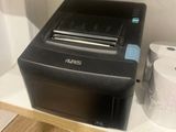 a printer sitting on top of a shelf next to a roll of toilet paper