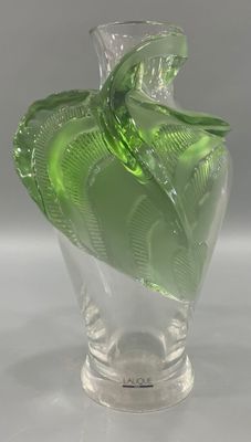 a glass vase with a green leaf decoration on it