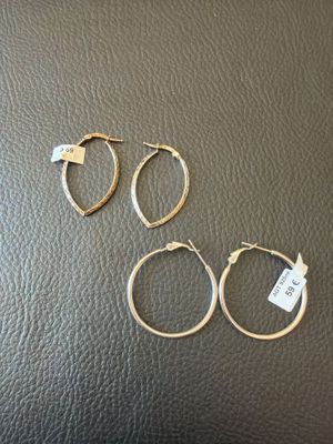 three pairs of gold hoop earrings on a black leather surface