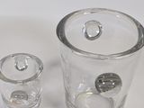 two glasses and a glass container sitting on a table