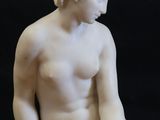 marble statue of a woman sitting on a rock with her hands on her knees