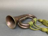 a brass trumpet with a green cord on a gray surface