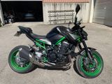 a black and green motorcycle parked in front of a garage