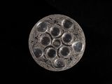 silver plate with black stones on it on a black background