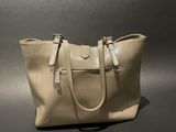 the large beige bag is sitting on a black surface