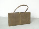 brown leather purse with gold metal handle on cement floor