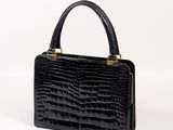 a black crocodile skin handbag on a white background