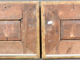 pair of old wooden picture frames with holes in them on a gray surface