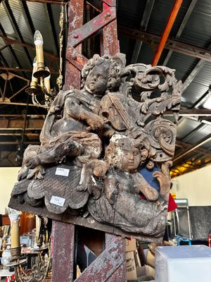 une grande sculpture en bois posée sur un socle dans un entrepôt