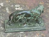 une statue en bronze représentant un lion sur un socle