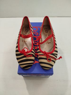 des chaussures rayées rouges et noires posées sur une boîte bleue, elle-même posée sur une surface blanche