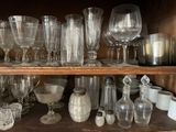 many glasses and vases on a shelf in a cabinet