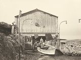 une vieille photo en noir et blanc représentant un bateau devant une maison