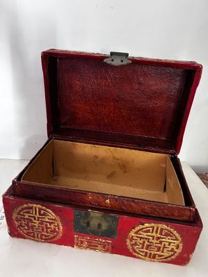 une petite boîte rouge ornée d'un motif doré