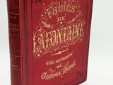 un livre rouge avec des lettres dorées posé sur une surface blanche