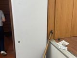 a white refrigerator and a red fire hydrant in a room