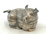 une figurine en argent représentant un cochon, posée sur un fond blanc