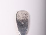 a silver spoon with a design on it on a white surface