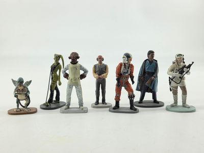 Les figurines des personnages de Star Wars sont alignées sur une surface blanche.