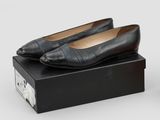 pair of black leather shoes sitting on top of a black box