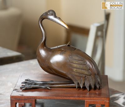 une statue représentant une grue posée sur un socle en bois