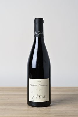 the bottle of wine is sitting on a wooden table
