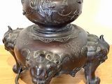 a bronze vase with elephants on it on a wooden table