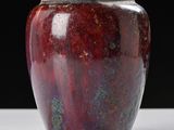 a red vase sitting on a table with a black background