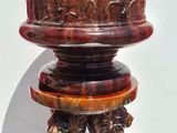 a red vase with animals on it sitting on a stand