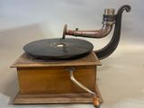 an old fashioned record player with a wooden stand and a metal pipe