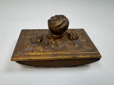 une vieille boîte en bronze ornée d'une fleur sur un fond blanc