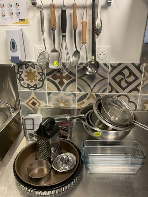 Les casseroles et les poêles sont posées sur un plan de travail de cuisine équipé d'un évier.