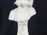 a white marble bust of a young girl with a black background
