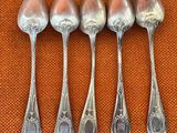 six cuillères en argent sont alignées sur une nappe orange