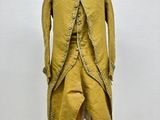 a yellow coat on a mannequin stand with a white wall in the background